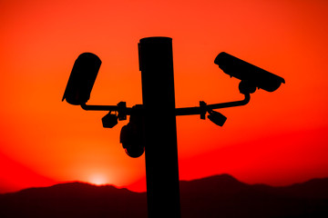 Close up silhouette of Security CCTV camera with sunset background