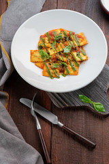 Classic ravioli with tomato sauce and Basil leaves on a white plate, rustic style