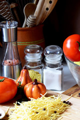 raw thread noodles next to tomatoes, spices and kitchen utensils