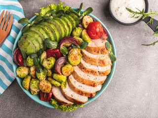 roasted sliced chicken fillet with brussels sprouts, tomatoes and herbs on a plate healthy food