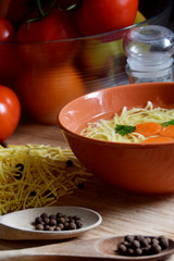 delicate chicken broth in a bowl next to tomatoes, spices and kitchen utensilsdelicate chicken broth in a bowl next to tomatoes, spices and kitchen utensils