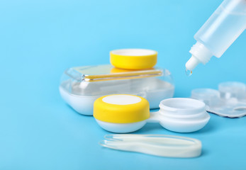 Containers for contact lenses, solution and tweezers on color background