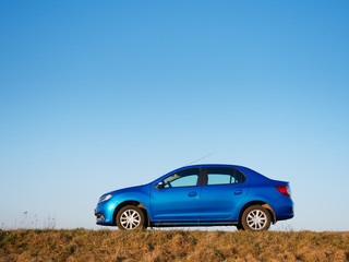 Obraz na płótnie Canvas Belarus blue car in a field in spring at sunrise