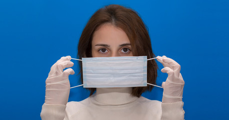 Woman in gloves and puts on a mask. Blue background