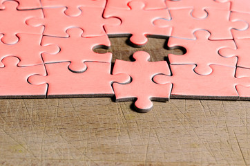 the unexpected solution.
pink jigsaw/puzzle with one piece at wrong position, on a wooden table...