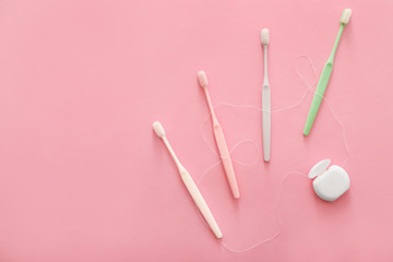 Tooth brushes and floss on color background