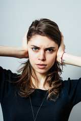 Woman covering ears with his hands. Gray background