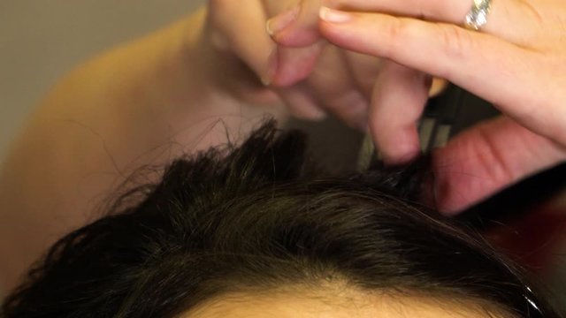 The stylist combs out the curled hair of a brunette girl