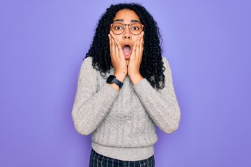 Young african american woman wearing casual sweater and glasses over purple background afraid and shocked, surprise and amazed expression with hands on face