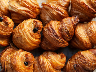 Freshly backed french traditional pastry - chocolate croissants shiny in the rays of the sun.