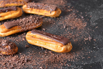 Tasty chocolate eclairs on dark background