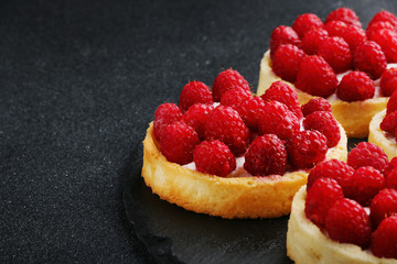 raspberries tart on the table. Fruit raspberry tart cakes on a black table.