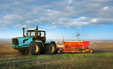 Big tractor with a seeder, cultivated soil on fields Ukraine at spring. Farmers prepare the land, tractor with a seeder, sowing time