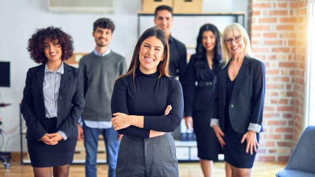 Group of business workers smiling happy and confident. Posing together with smile on face looking at the camera, young beautiful woman with crossed arms at the office