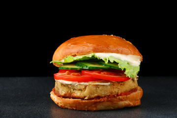 fresh tasty vegan burger on black isolated background. tomato, onion, vegan mayonnaise. Vegan chickpeas burgers with arugula, pickled cucumbers and hummus. Plant based diet concept.