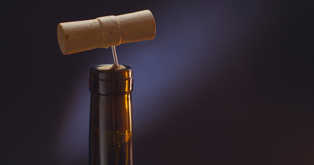 corked wine bottle with corkscrew on black background
