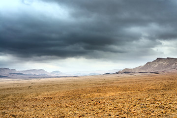 At the bottom of the deserted rocky vally under the stormy cloudy sky.