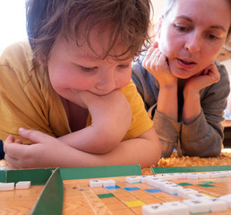 Children play in Russian Scrabble on the floor. Board game Chips are lined in a crossword. Education, leisure concept Back to school