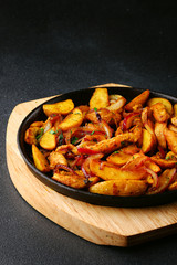 frying pan with potatoes meat and roast onion on black concrete background. mexican food concept. potatoes fried in a pan
