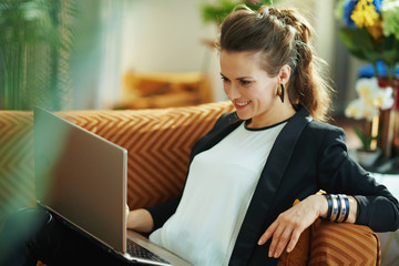 woman at modern home in sunny day writing while sitting on sofa