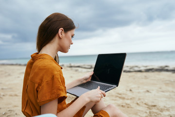 young woman with laptop on the beach