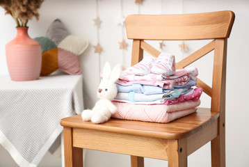 Baby clothes with booties and toy on chair in room