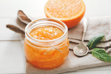 Jar of orange jam on white table