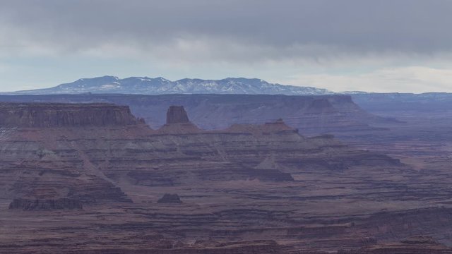 A long-lens timelapse looking across at a distant mesa in Canyonlands National Park, as seen from Dead Horse Point State Park on a cloudy winter afternoon.