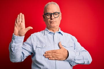 Middle age handsome hoary man wearing casual striped shirt and glasses over red background Swearing...