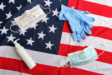 Frame from used protective masks, gloves and sanitizer pump bottle on american flag background. Covid-19 quarantine. Flat lay, top view, copy space