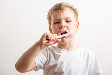 cute boy posing with bamboo toothbrush in his mouth, child brushes his teeth