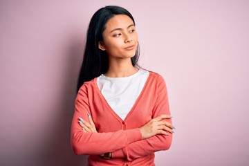 Obraz premium Young beautiful chinese woman wearing casual sweater over isolated pink background looking to the side with arms crossed convinced and confident