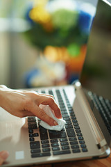 Closeup on female wiping laptop with cleaning cloth