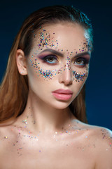 Beauty portrait of a beautiful sexy girl with bright makeup and sparkles in the shape of a mask on her face.