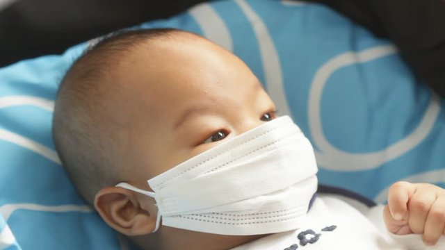 mother putting on Protective mask to her son to protect from Corona virus or Covid-19 virus outbreak, Covid-19 Coronavirus concept. Virus and illness protection. newborn not good mood