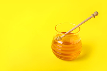 Jar of sweet honey on color background