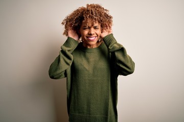 Obraz na płótnie Canvas Beautiful african american woman with curly hair wearing casual sweater over white background Trying to hear both hands on ear gesture, curious for gossip. Hearing problem, deaf