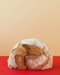 Round homemade bread on a colored background with space for text. Art concept of baking, food. Vertical photo.