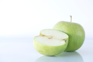 Whole green apple and a half one on a white background, isolated, macro photography