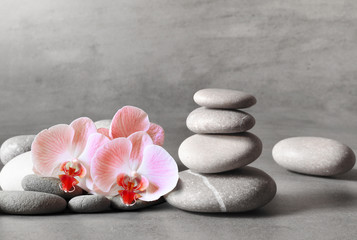 Naklejka na ściany i meble Spa stones and pink orchid on the grey background.