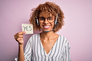 African american call center agent woman using headset holding reminder with yes message with a...