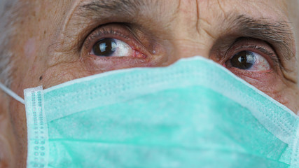 close view face of wrinkled mature senior man in medical facemask