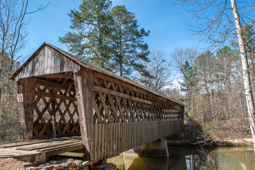Covered bridge in countryside with blue sky background.