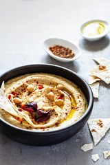 Classic hummus in a bowl with herbs, smoked paprika, olive oil and lettuce on a blue (gray) background. Healthy vegan food. A dish of Middle Eastern cuisine. Healthy eating concept.