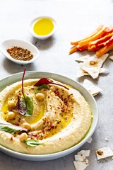 Classic hummus in a bowl with herbs, smoked paprika, olive oil and lettuce on a blue (gray) background. Healthy vegan food. A dish of Middle Eastern cuisine. Healthy eating concept.