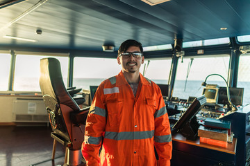 Filipino deck Officer on bridge of vessel or ship wearing coverall during navigaton watch at sea. - obrazy, fototapety, plakaty