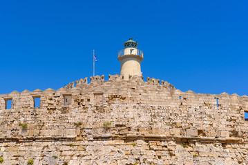 Wall with lighthouse of the fort of St. Nicholas in Mandrakia port of Rhodes. Greece