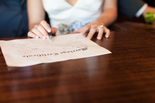 Bride holding pen signing marriage certificate