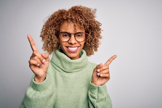 Young beautiful african american woman wearing turtleneck sweater and glasses smiling confident pointing with fingers to different directions. Copy space for advertisement