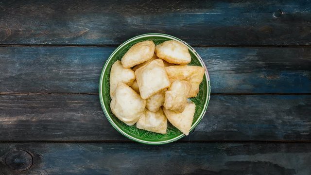 Baursak - traditional Kazakh Asia food national bread Rotates in plate on a beautiful wooden background. Top view